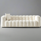 White tufted sofa with a single pillow against a gray background