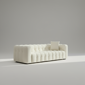 White tufted sofa with a single pillow against a gray background