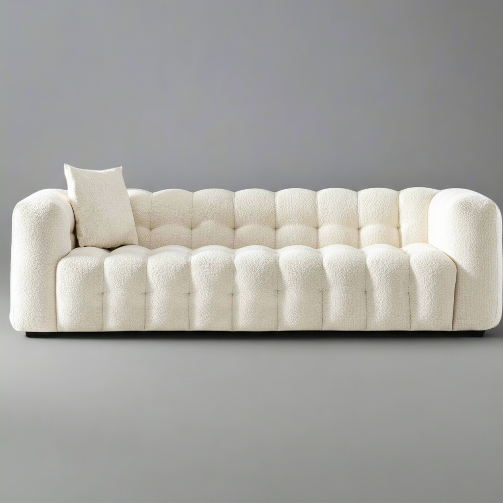 White tufted sofa with a single pillow against a gray background