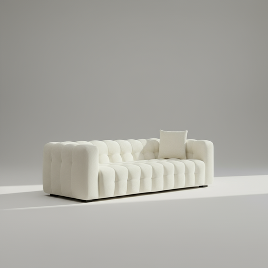 White tufted sofa with a single pillow against a gray background
