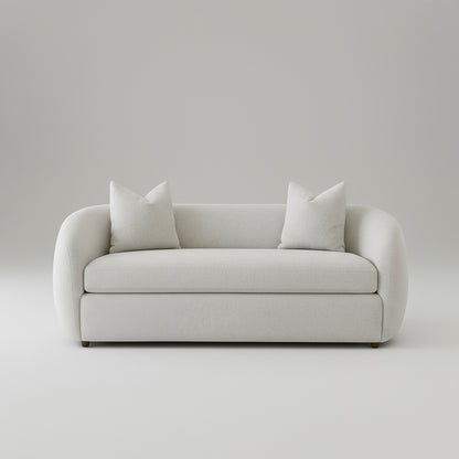 White sofa with white cushions in a room with plants and a wooden coffee table.