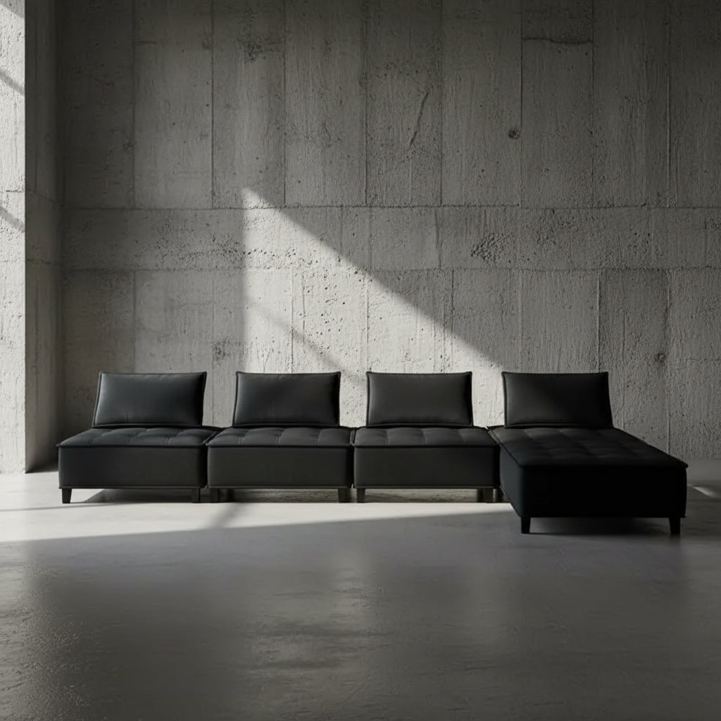 Black sectional sofa against a plain wall