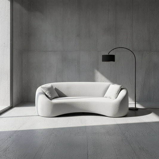 Modern gray sofa with two cushions in a minimalistic room with a floor lamp.