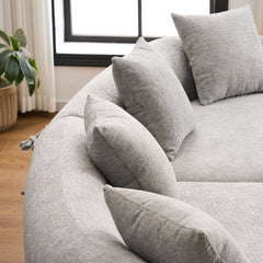 A styled living room featuring THE ORVILLE curved modular sectional in Stone Grey, showcasing the sculptural design and plush matching cushions in natural light.