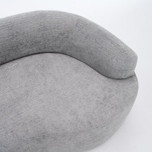 A side-angle view of the ORVILLE sofa’s curved backrest, showing the seamless Mist Grey chenille upholstery and soft, rounded architectural lines.